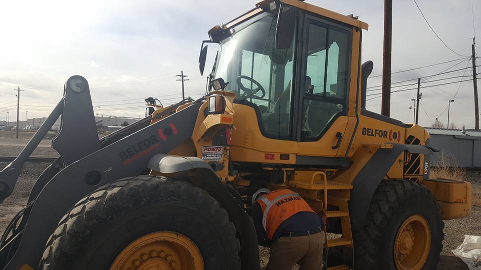 A man doing a daily maintenance check on heavy equipment.