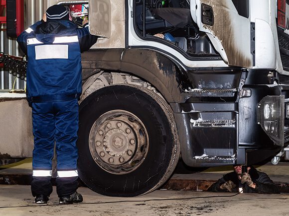 Two truck technicians are fixing truck electrical problems.