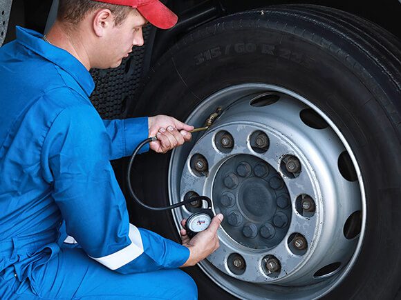 Truck Technician checking the tire pressure of the crane truck.