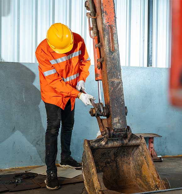 Technician removing excavator's bucket.