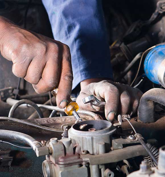 A closeup of the hands of a technician repairing a vehicle's engine.
