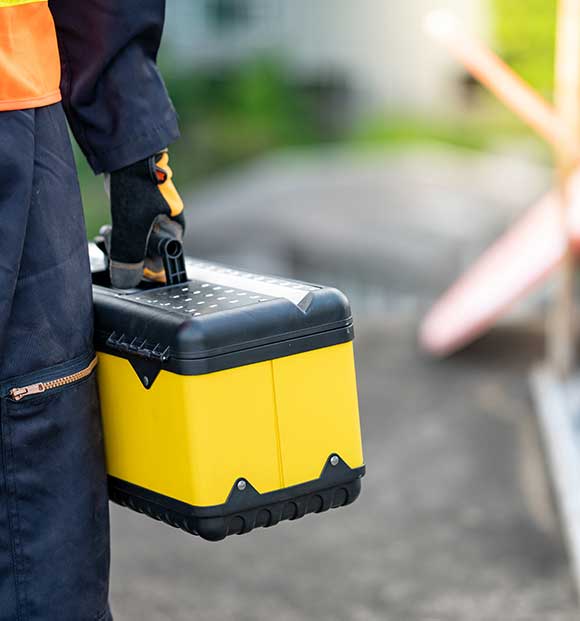 EMT Male maintenance worker hand carrying yellow work tool box at construction site