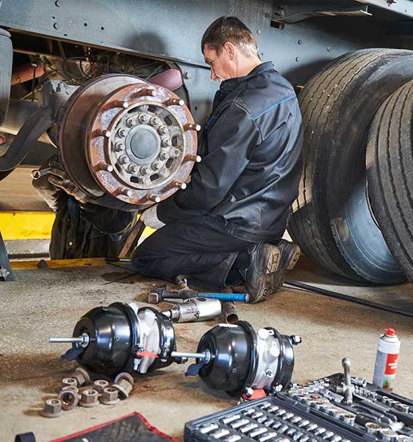 A truck technician works with brakes in the truck workshop.