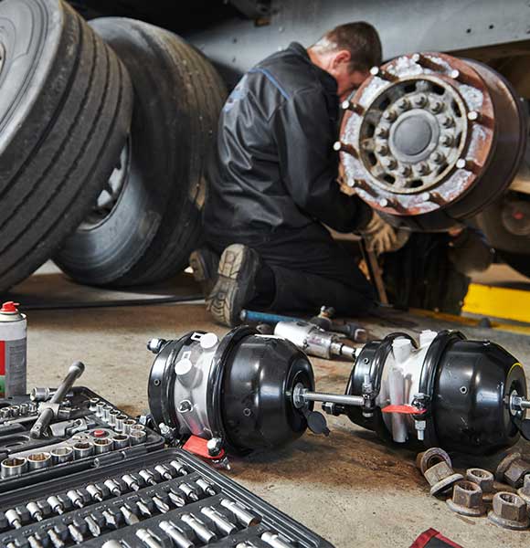 EMT Mechanic works with brakes in truck workshop