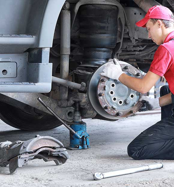 EMT mechanic repairs the brakes of a truck.