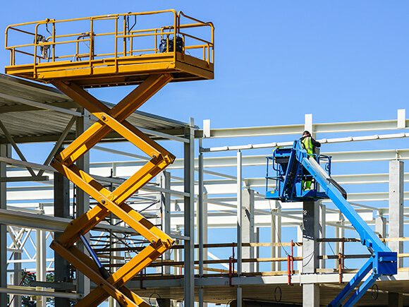 A yellow and blue scissor lift is on site.