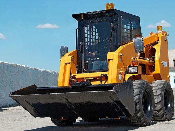 A man drives a skid steer loader.