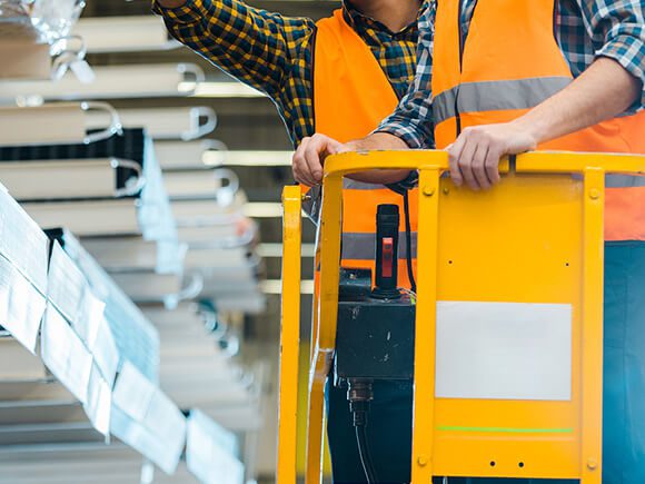 Two workers standing on a vertical lift machine platform.